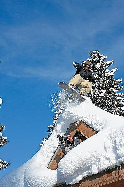 A tourist snowboards down a hotel roof in Gulmarg
