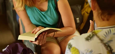 A women engrossed in a book while travelling