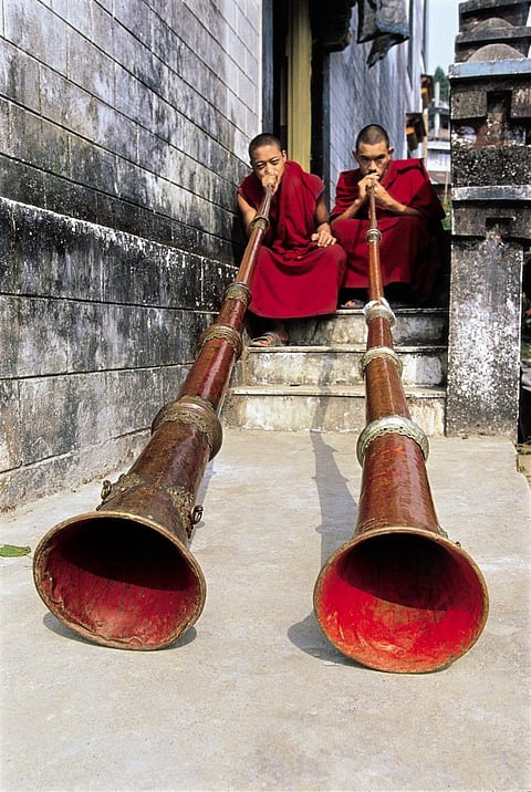 Monks learning to blow horns at a monastery