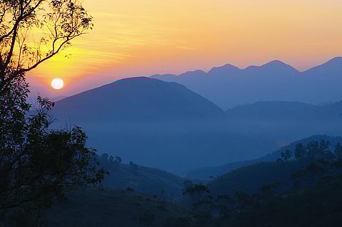 The sun rises over mist-covered hills in Vagamon.