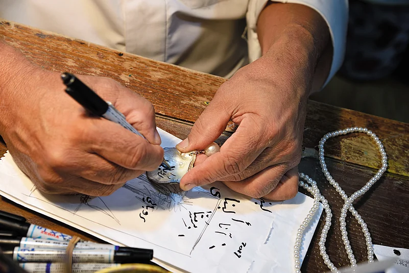 An artisan writes on a shell souvenir