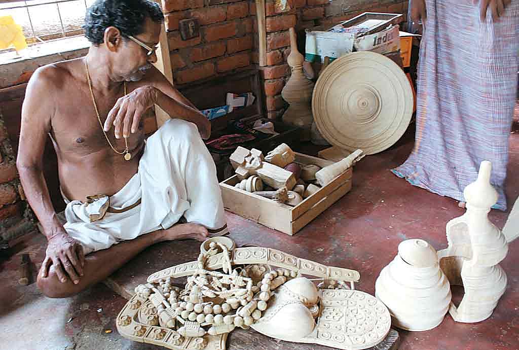 An artist works in his studio making wooden carvings