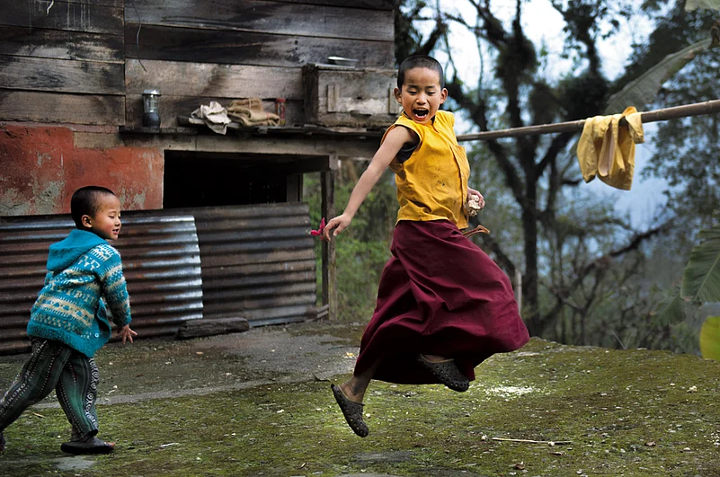 A young monk dodges a pellet of dough in a friendly game in Lingthem village, Upper Dzongu