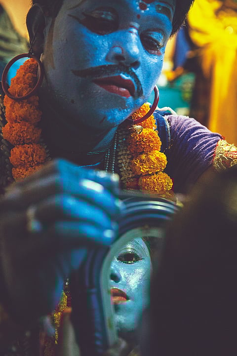 A Jatra performer applies makeup to a fellow actor