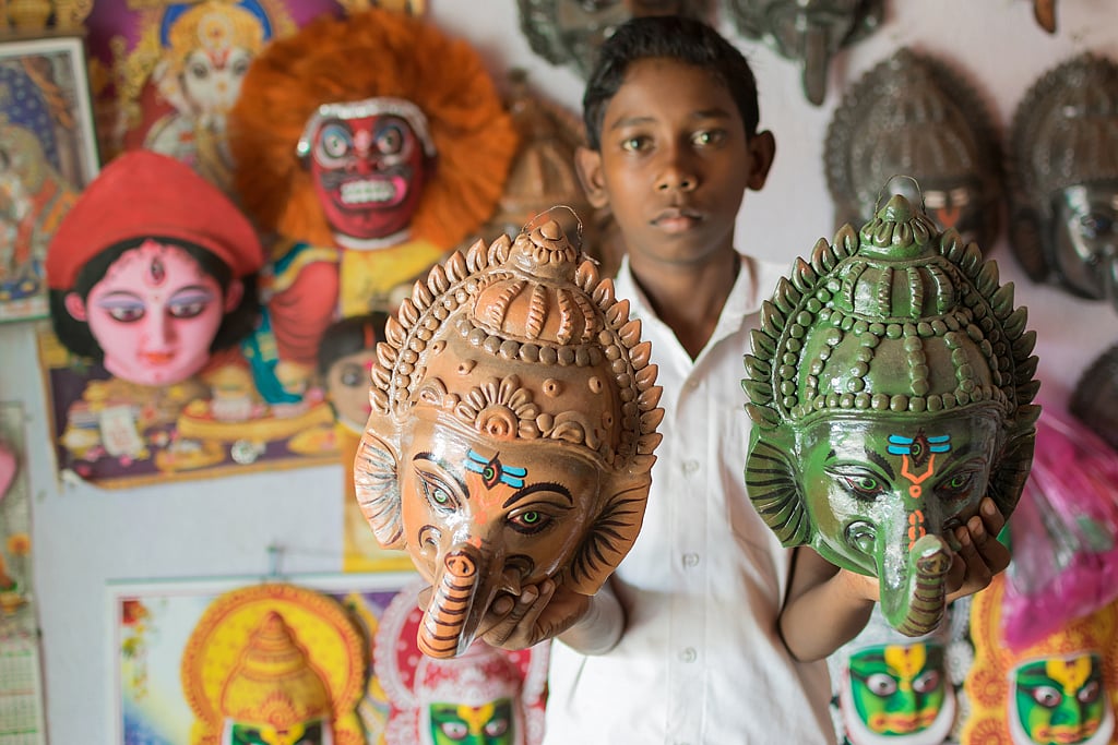 An artisan in Charida village displays masks for interior decoration