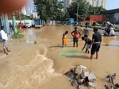 ಜಲಾವೃತವಾದ ಪ್ರದೇಶದಲ್ಲಿ ಬಲೆ ಹಾಕಿ ಮೀನು ಹಿಡಿಯುತ್ತಿರುವ ಹುಡುಗರು