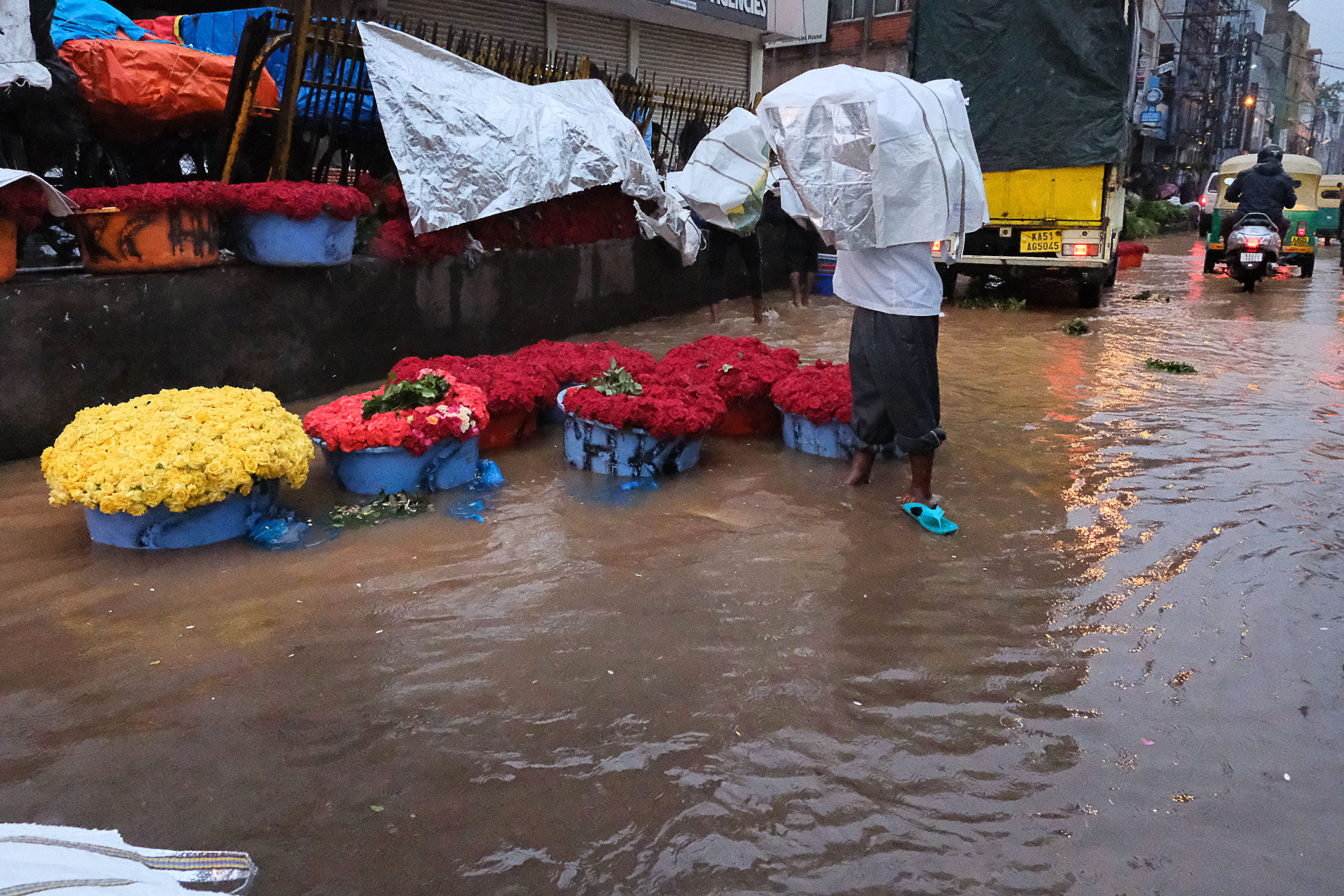 ಕೆ.ಆರ್. ಮಾರುಕಟ್ಟೆಯ ರಸ್ತೆಯಲ್ಲಿ ಸಂಗ್ರಹಗೊಂಡ ಮಳೆ ನೀರಿನಲ್ಲಿ ವ್ಯಾಪಾರಿಯೊಬ್ಬರು ಹೂವಿನ ಬುಟ್ಟಿಗಳನ್ನು ಇಟ್ಟಿಕೊಂಡಿದ್ದರು  