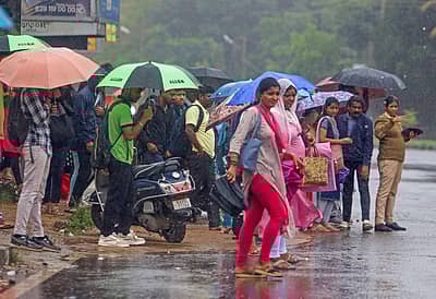 ಸುರಿಯುತ್ತಿರುವ ಮಳೆಯ ನಡುವೆ ಸಾರಿಗೆ ಬಸ್‌ಗಳಿಗೆ ಕಾಯುತ್ತಿರುವ ಪ್ರಯಾಣಿಕರು 