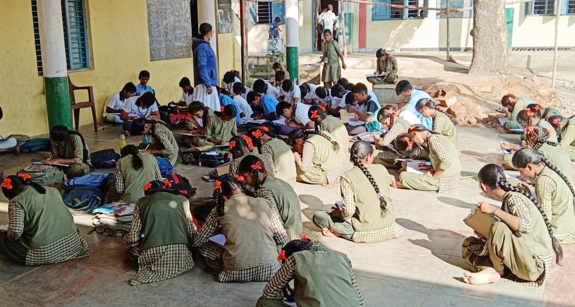 ಮರಿಯಮ್ಮನಹಳ್ಳಿ ಸಮೀಪದ ಹಂಪಿನಕಟ್ಟೆ ಗ್ರಾಮದ ಸರ್ಕಾರಿ ಪ್ರೌಢಶಾಲೆಯ ವಿದ್ಯಾರ್ಥಿಗಳು ಕೊಠಡಿಯೊಳಗೆ ಜಾಗ ಇಲ್ಲದೆ ಶಾಲೆಯ ಜಗಲಿ ಮತ್ತು ಬಯಲಲ್ಲಿ ಕೂತಿರುವುದು
–ಪ್ರಜಾವಾಣಿ ಚಿತ್ರ