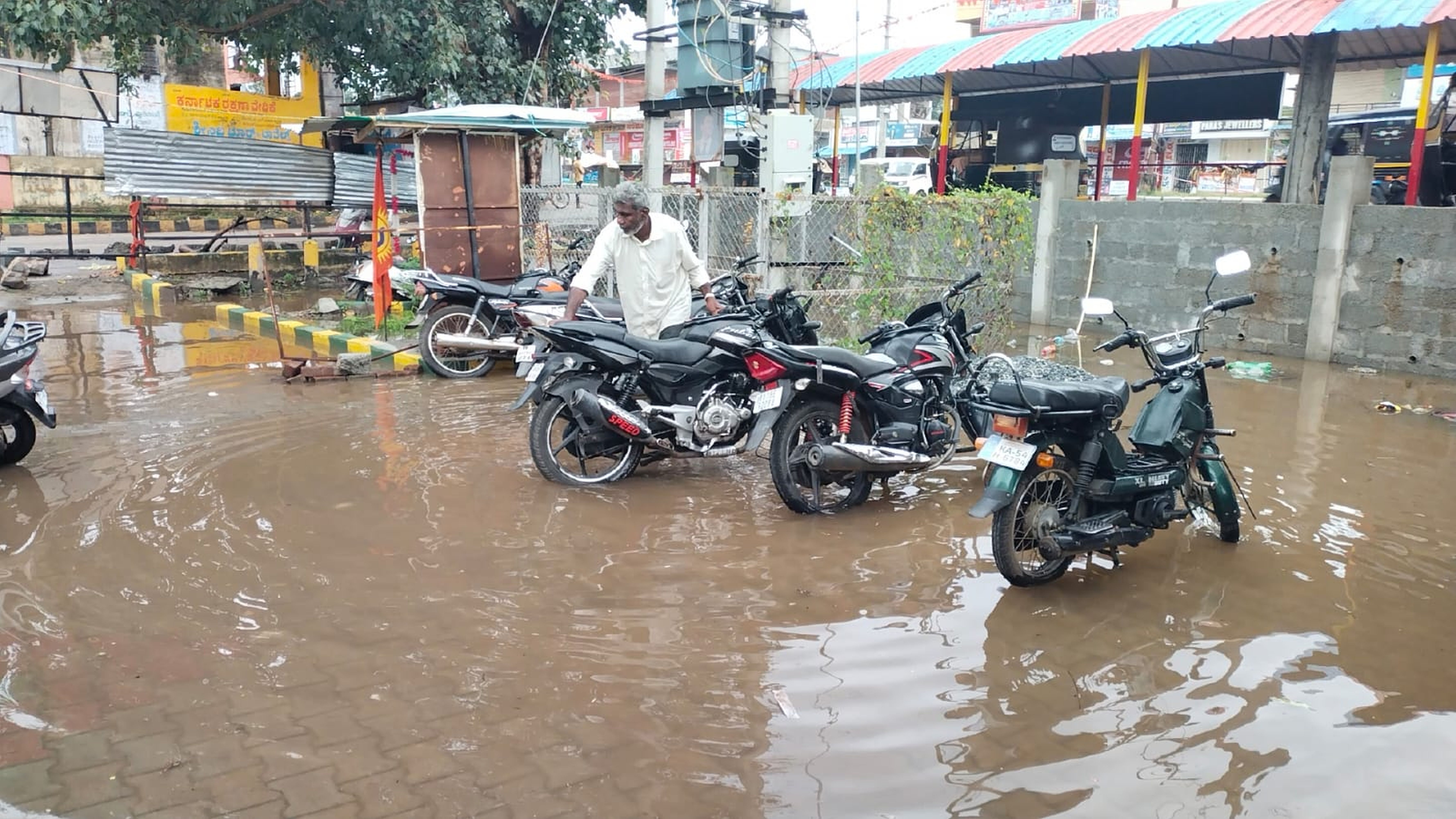 ಬಸ್‌ ನಿಲ್ದಾಣದಲ್ಲಿ ನಿಂತಿರುವ ನೀರಿನಲ್ಲಿ ಬೈಕ್‌ ಸವಾರರ ಪರದಾಟ 