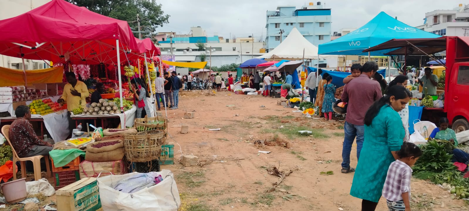 ಹೊಸಕೋಟೆ ನಗರದ ಹೂ ಮಂಡಿ ಸರ್ಕಲ್ ಬಳಿಯ ಖಾಲಿ ಮೈದಾನದಲ್ಲಿ ಜನರಿಂದ ಮಳಿಗೆಗಳಲ್ಲಿ ಹೂ ಹಣ್ಣು ಖರೀದಿಯಲ್ಲಿ ನೀರಸ ಪ್ರತಿಕ್ರಿಯೆ ವ್ಯಕ್ತವಾಗುತ್ತಿರುವುದು