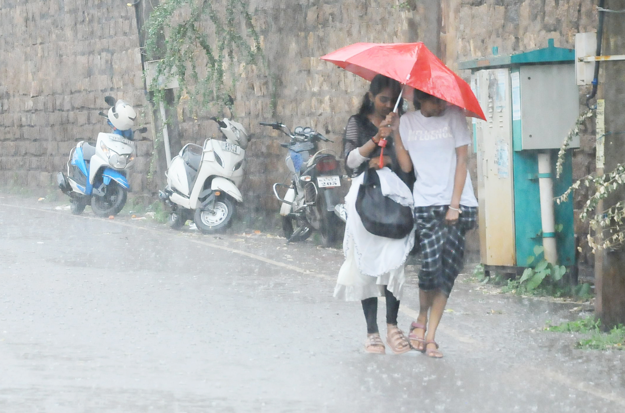 ಮಳೆಯಲ್ಲಿ ಕೊಡೆ ಹಿಡಿದು ಸಾಗಿದ ಯುವತಿಯರು