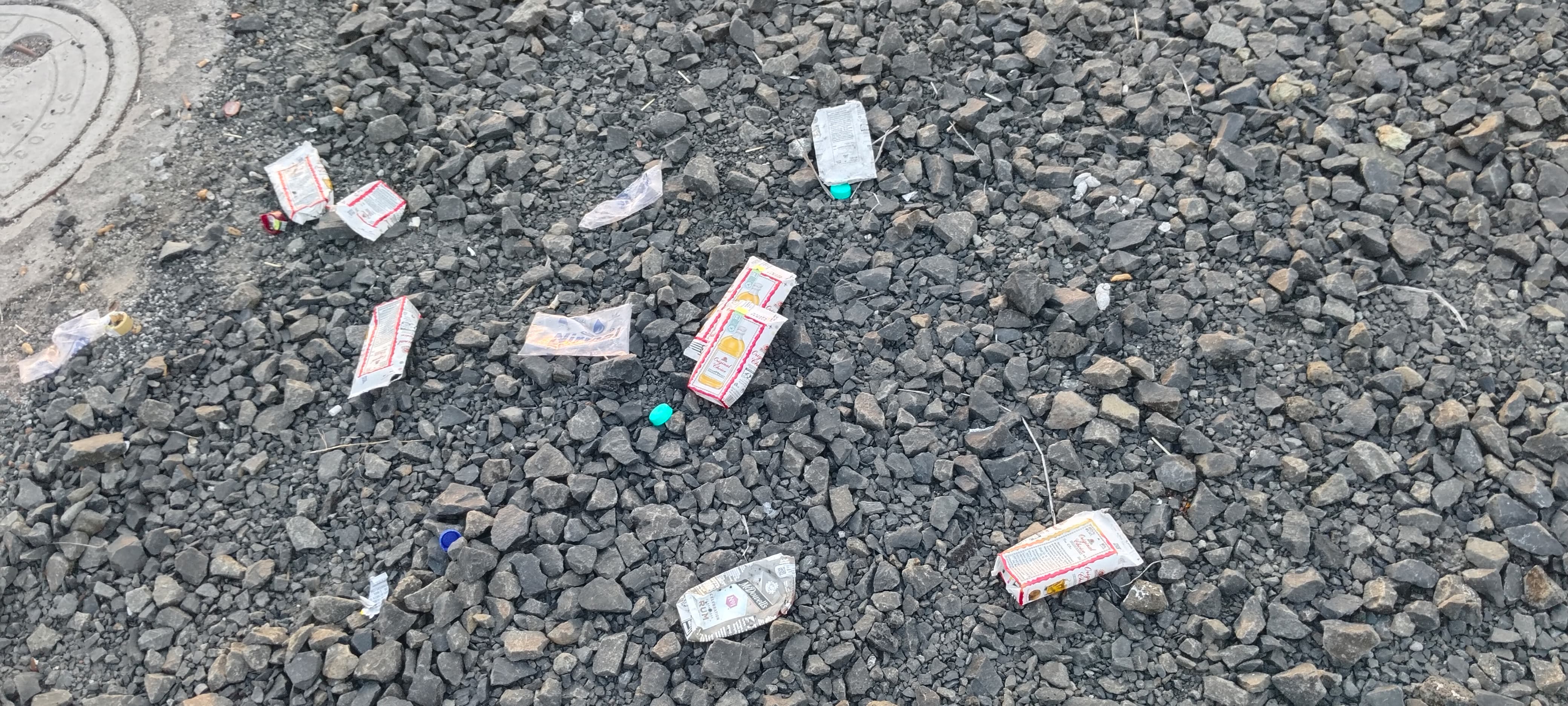 ರಸ್ತೆ ಮೇಲೆ ಬಿದ್ದಿರುವ ಮದ್ಯದ ಪ್ಯಾಕೆಟ್‌ಗಳು