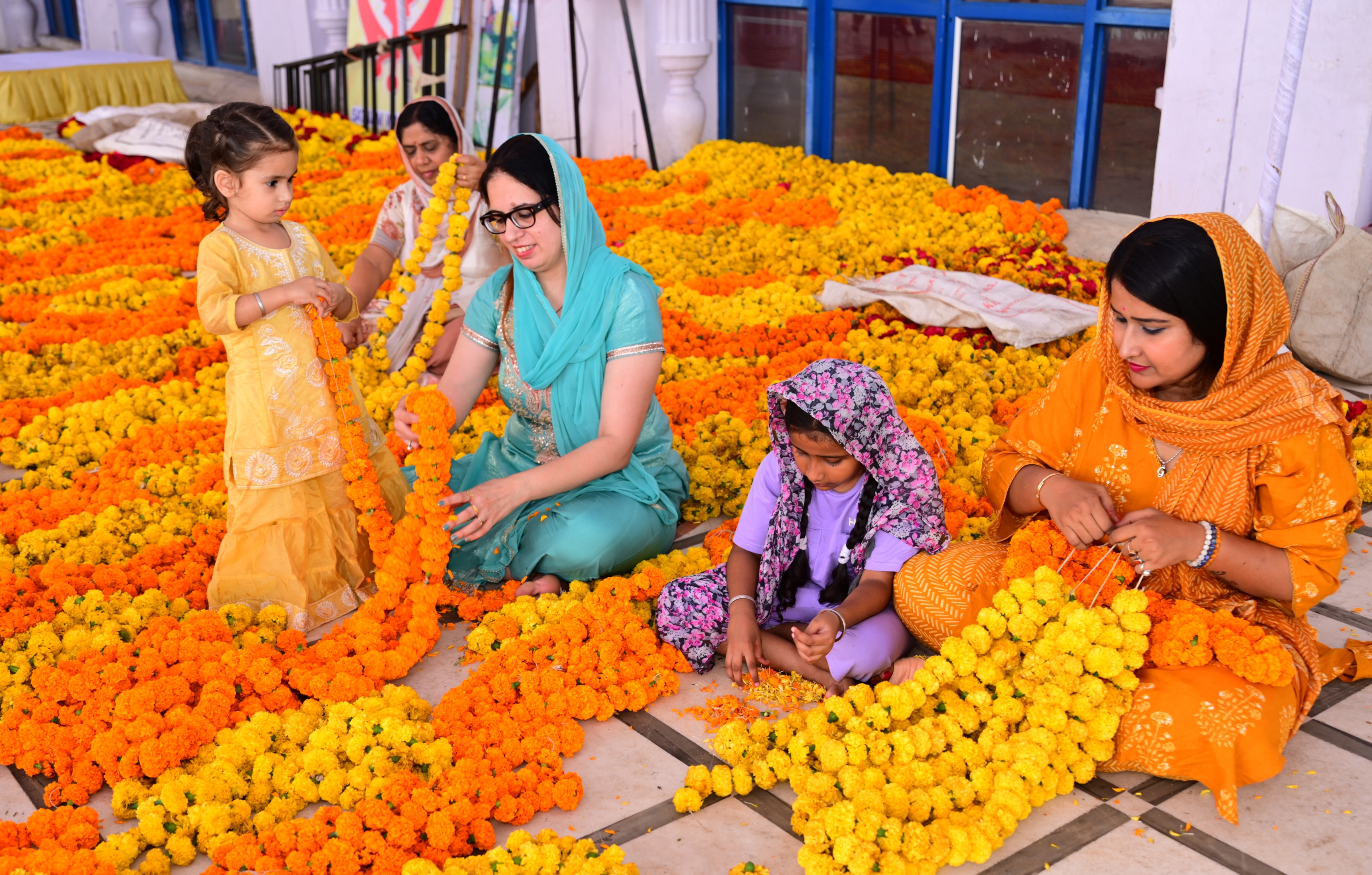ಗುರುದ್ವಾರ ಅಲಂಕರಿಸಲು ಹೂವಿನ ಮಾಲೆ ತಯಾರಿಸುತ್ತಿರುವ ಮಹಿಳೆಯರು