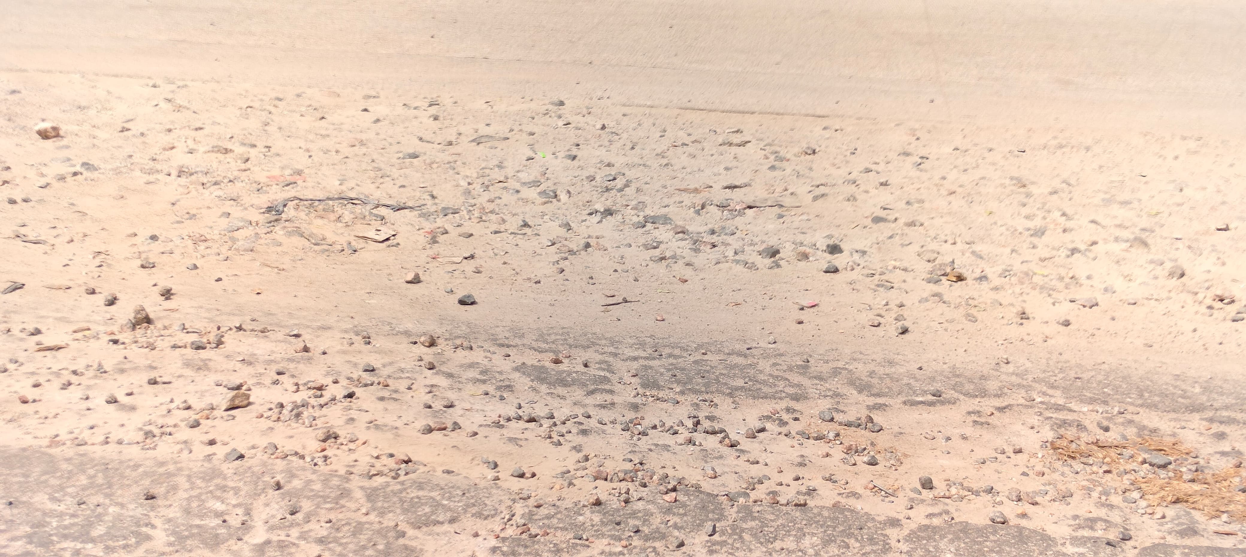 ರಸ್ತೆಯ ಮೇಲೆ ಬಿದ್ದಿರುವ ಜಲ್ಲಿ ಕಲ್ಲು ಮತ್ತು ಧೂಳು 