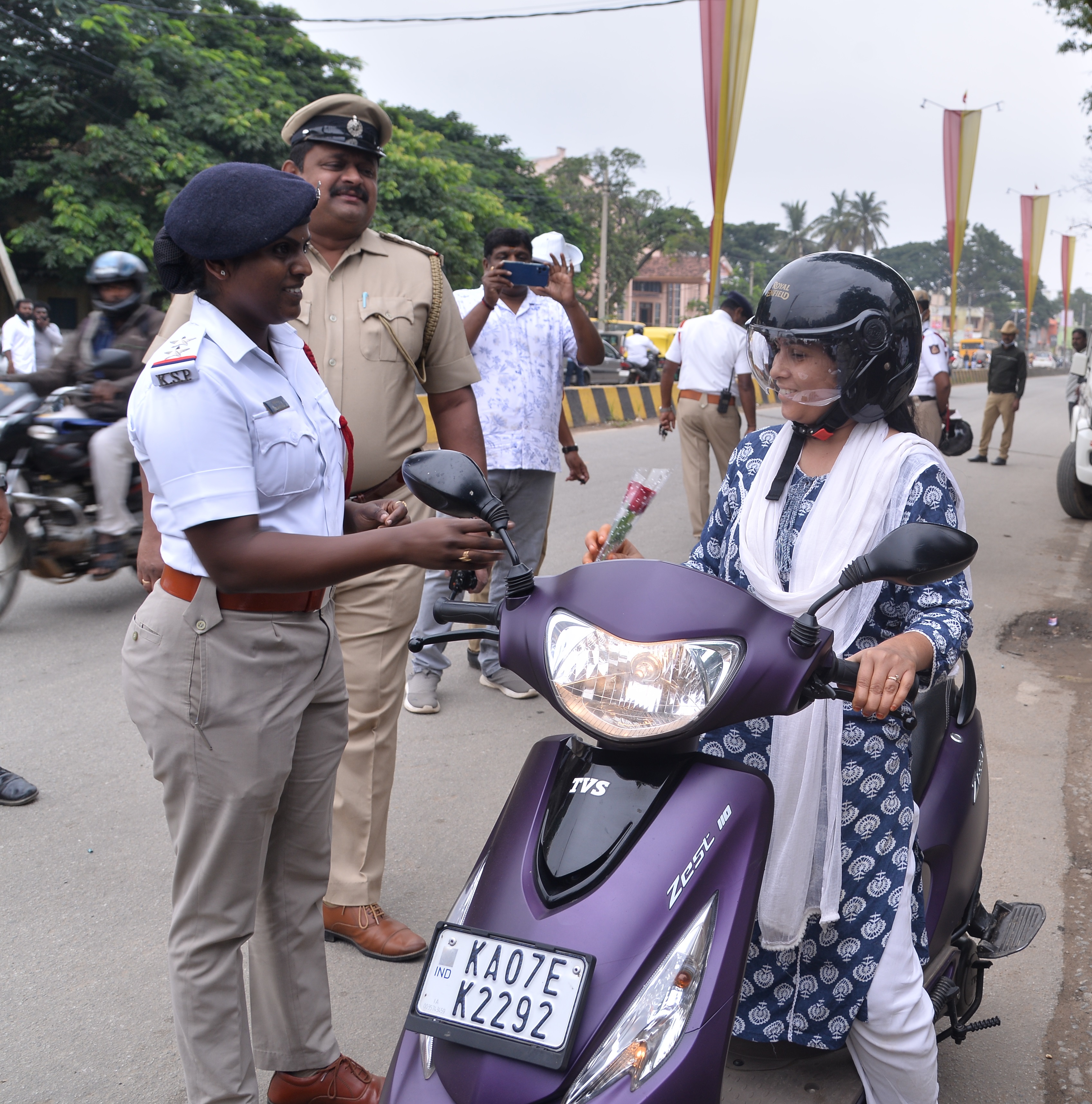 ಹೆಲ್ಮೆಟ್‌ ಧರಿಸಿ ಬಂದ ಮಹಿಳೆಗೆ ಸರ್ಕಲ್‌ ಇನ್‌ಸ್ಪೆಕ್ಟರ್‌ ಲೋಕೇಶ್‌ ಹಾಗೂ ಸಂಚಾರ ಪೊಲೀಸ್‌ ಠಾಣೆ ಪಿಎಸ್‌ಐ ಭಾರತಿ ಗುಲಾಬಿ ಹೂವು ನೀಡಿದರು