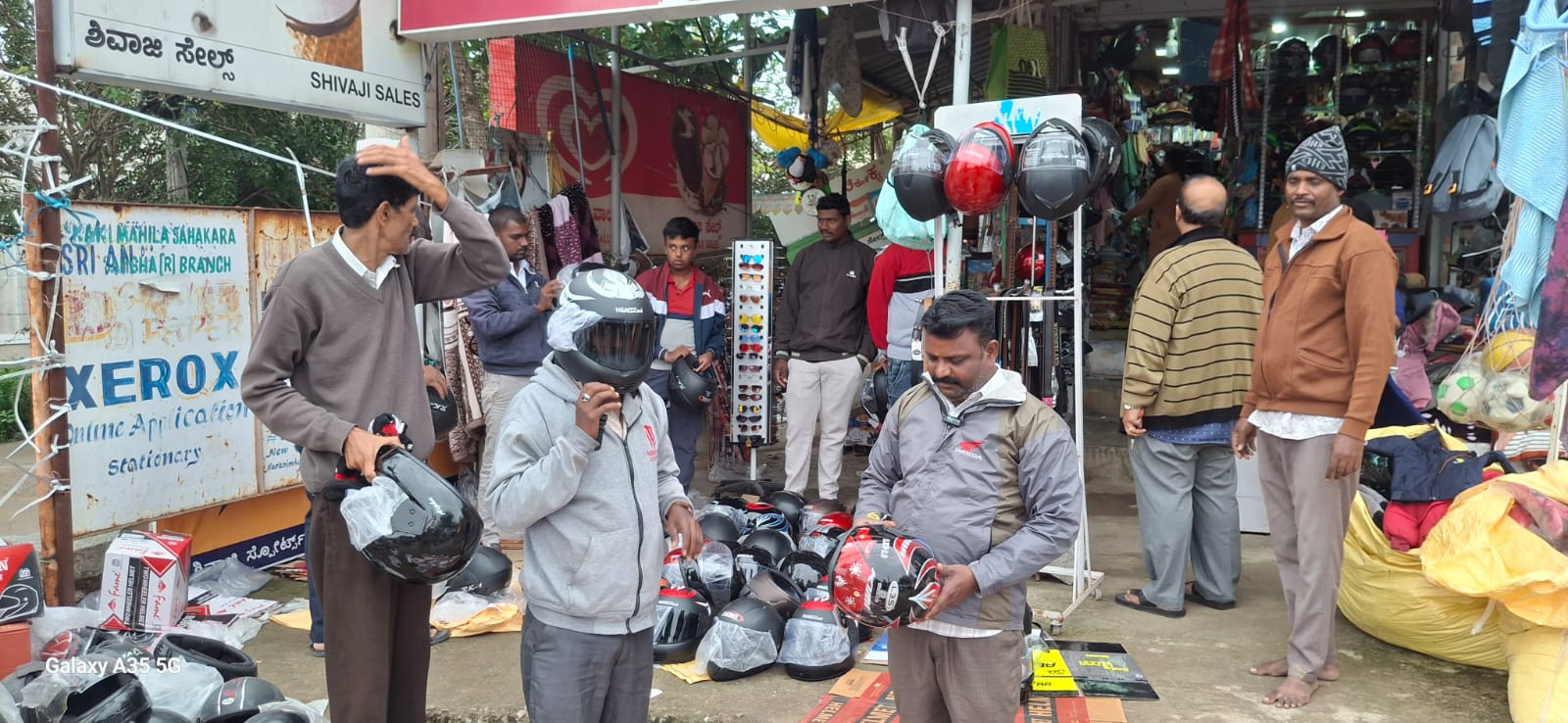 ಹೆಲ್ಮೆಟ್ ಖರೀದಿಸಲು ಮುಳಬಾಗಿಲು ಅಂಗಡಿಯೊಂದರ ಮುಂದೆ ಸೇರಿರುವ ವಾಹನ ಸವಾರರು