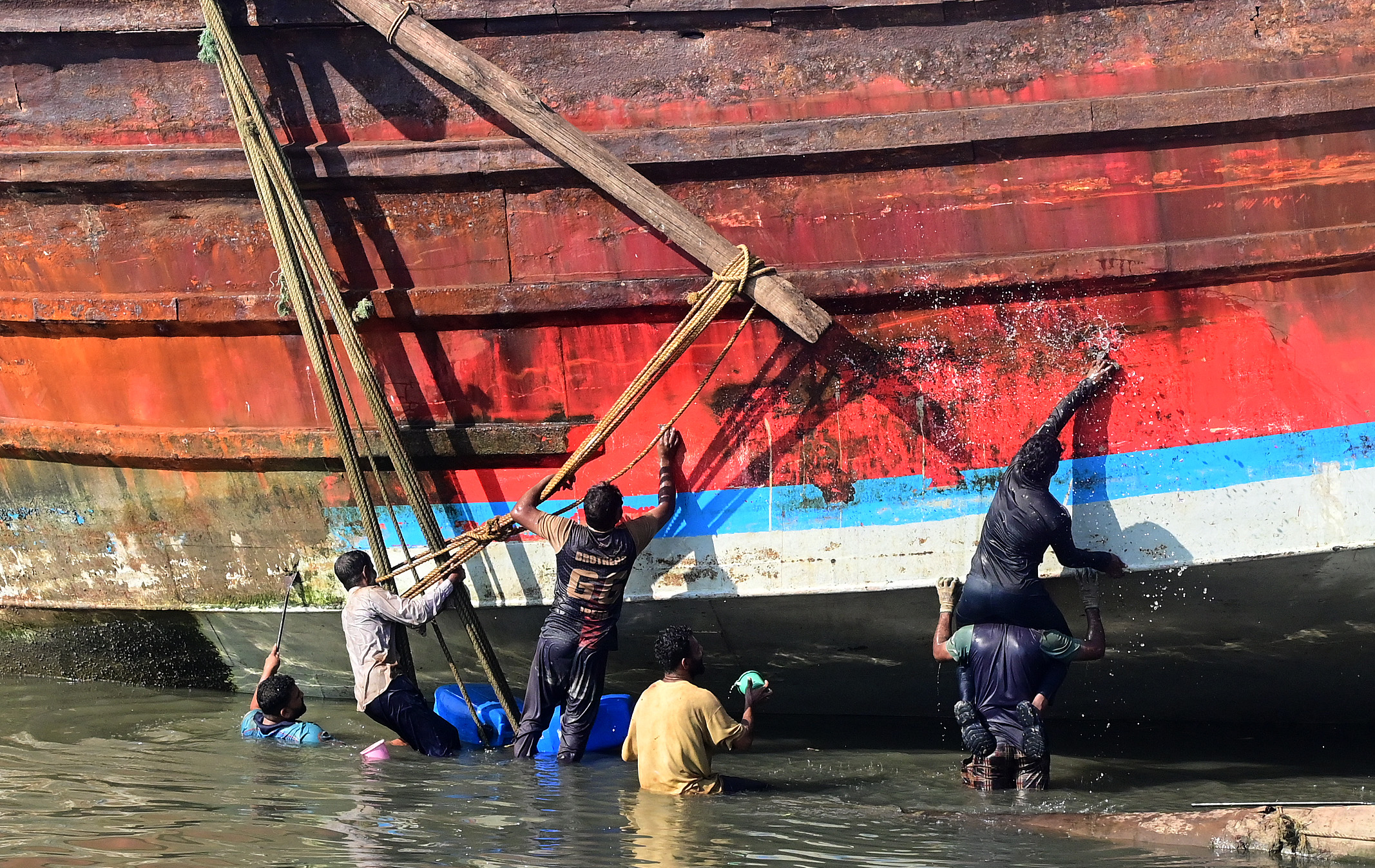 ದಕ್ಕೆಯಲ್ಲಿ ನಿಲ್ಲಿಸಿರುವ ದೋಣಿಯನ್ನು ಶುಚಿಗೊಳಿಸಿದ ಕಾರ್ಮಿಕರು