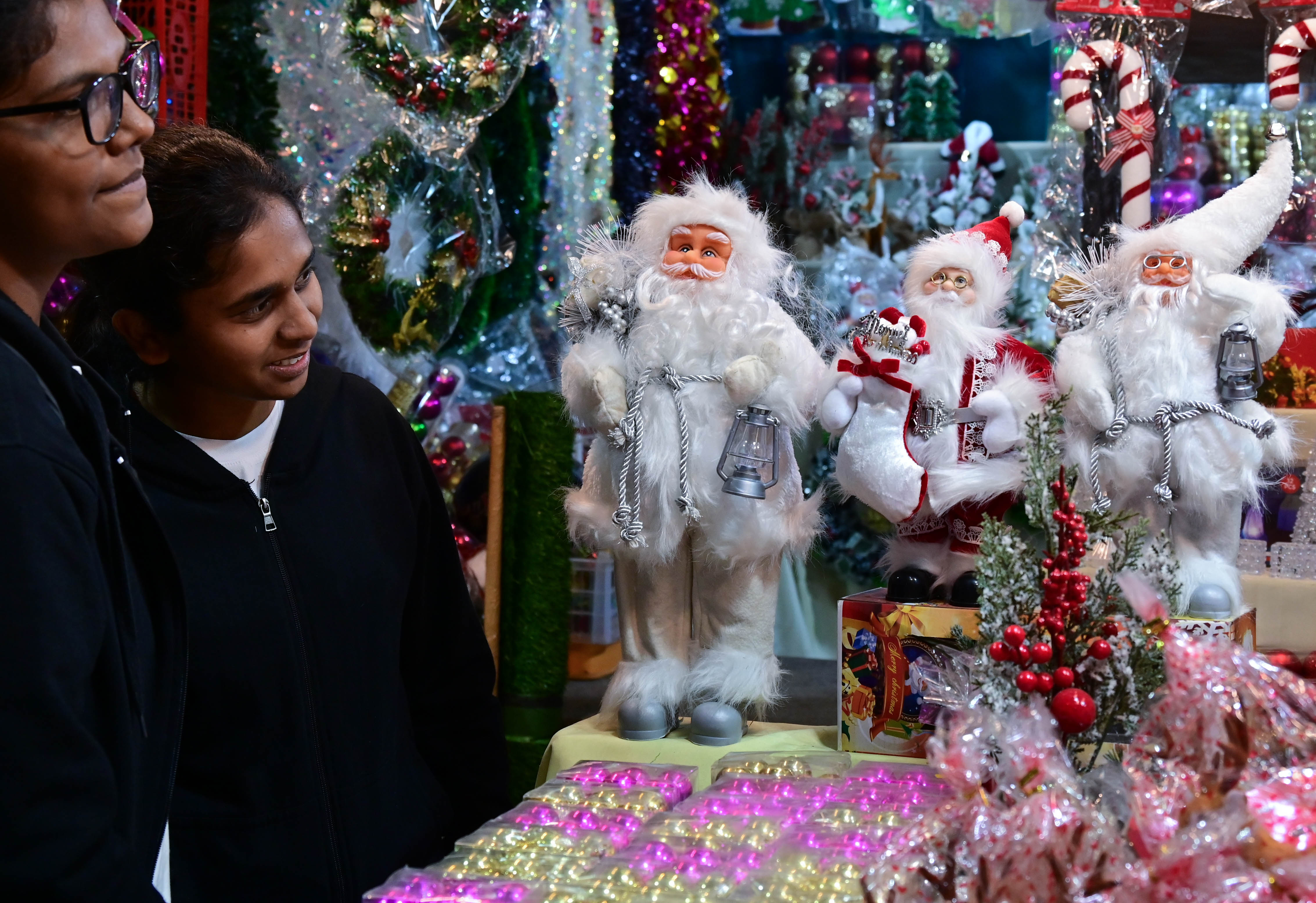 ಸಂತಾಕ್ಲಾಸ್‌ ಬೊಂಬೆಗಳನ್ನು ಕುತೂಹಲದಿಂದ ವೀಕ್ಷಿಸಿದ ಯುವತಿಯರು