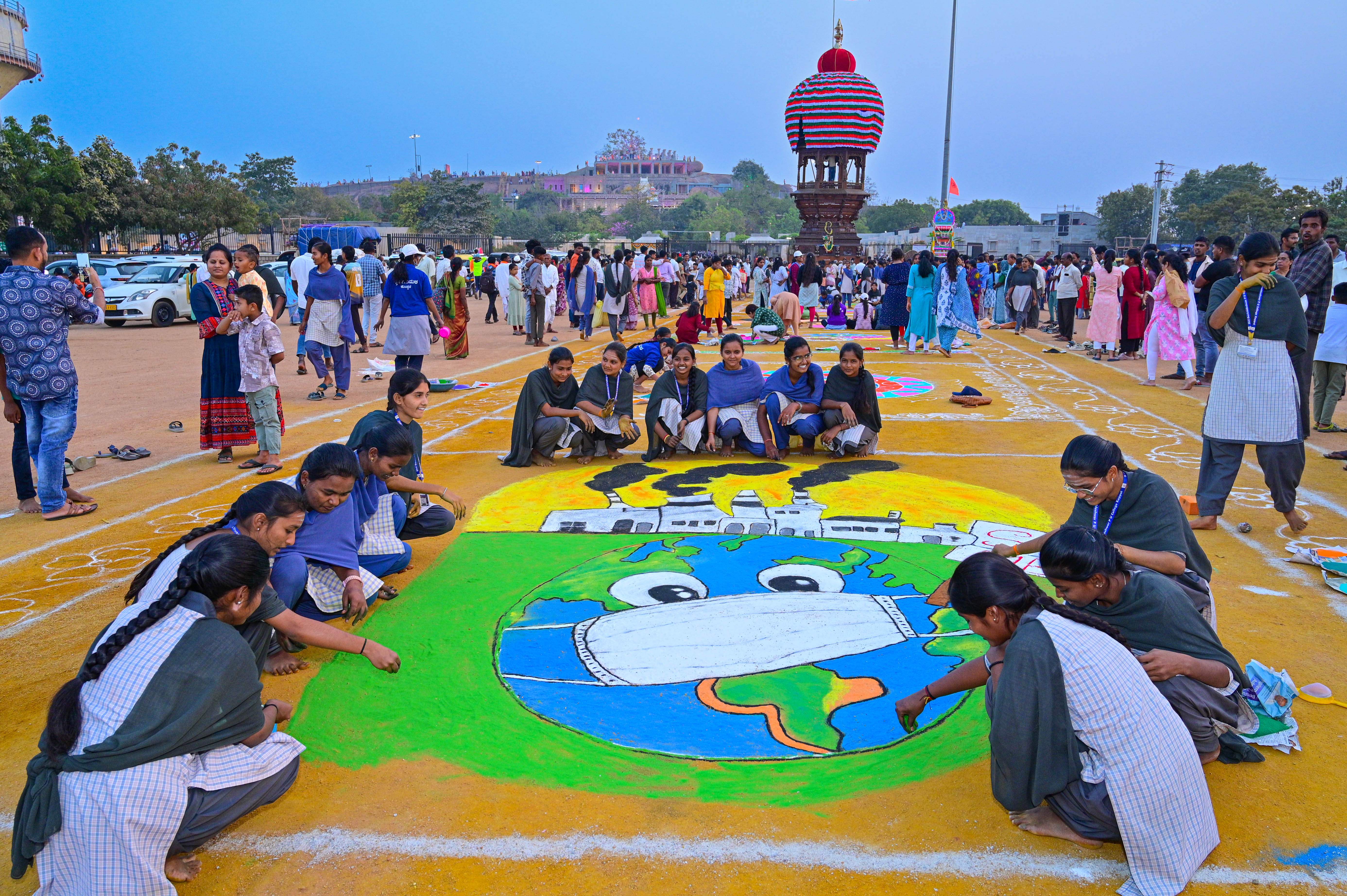 ಗವಿಸಿದ್ಧೇಶ್ವರ ರಥೋತ್ಸವ ಸಾಗುವ ಮಾರ್ಗದಲ್ಲಿ ಕಾರ್ಖಾನೆಗಳನ್ನು ತೊಲಗಿಸಿ ಭೂಮಿ ಉಳಿಸಿ ಎಂಬ ಸಂದೇಶ ಸಾರುವ ರಂಗೋಲಿ ಬಿಡಿಸುವಲ್ಲಿ ಕಂಡ ಯುವತಿಯರು