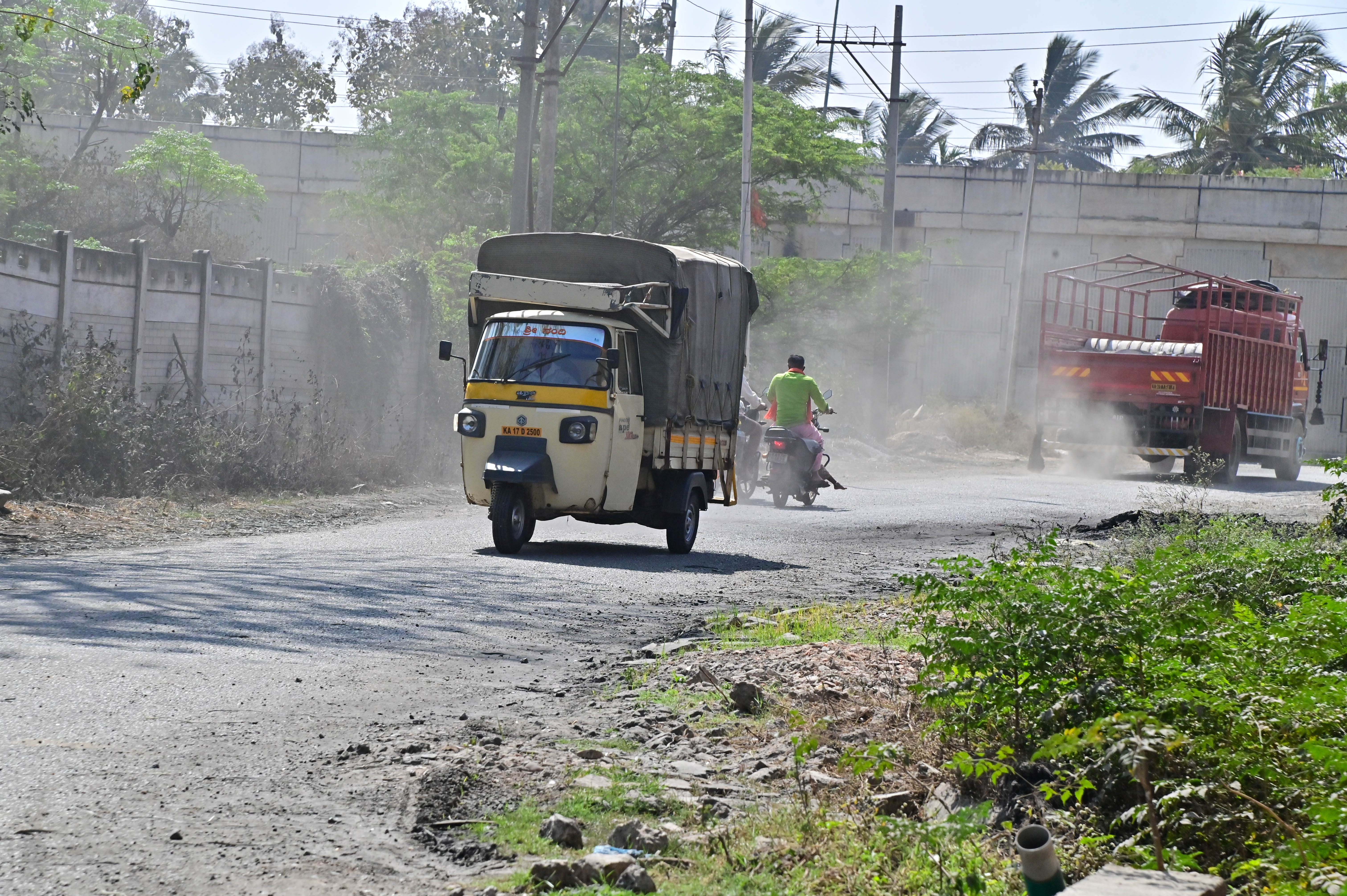 ಹನಗವಾಡಿ ಬಳಿಯ ಕೆಐಎಡಿಬಿ ಕೈಗಾರಿಕಾ ಪ್ರದೇಶದ ದೂಳುಮಯ ರಸ್ತೆಯಲ್ಲಿ ವಾಹನ ಸವಾರರು ಸಂಚರಿಸುತ್ತಿರುವುದು
