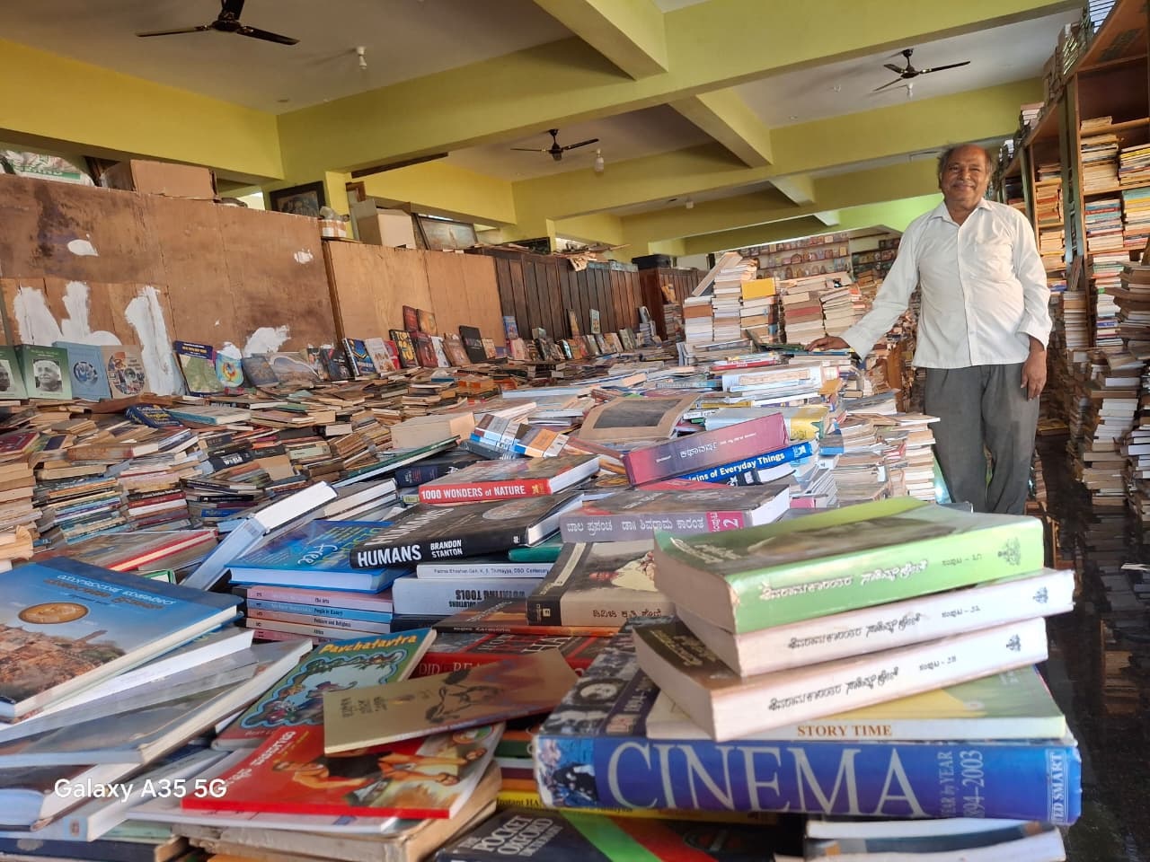 ಪಾಂಡವಪುರದ ‘ಪುಸ್ತಕ ಮನೆ’ ಗ್ರಂಥಾಲಯದಲ್ಲಿ ನೆಲದ ಮೇಲೆ ಸುರಿದಿರುವ ಪುಸ್ತಕಗಳ ರಾಶಿಗಳ ನಡುವೆ ಎಂ. ಅಂಕೇಗೌಡ