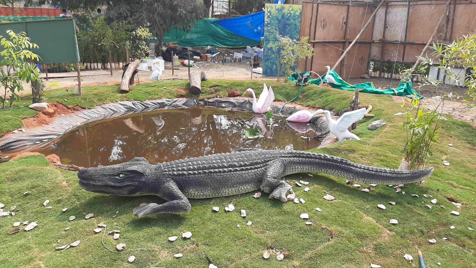 ಕೃತಕ ಕೊಳದ ದಡದ ಮೇಲೆ ಹೊಂಚು ಹಾಕಿ ಕುಳಿತಿರುವ ಮೊಸಳೆ