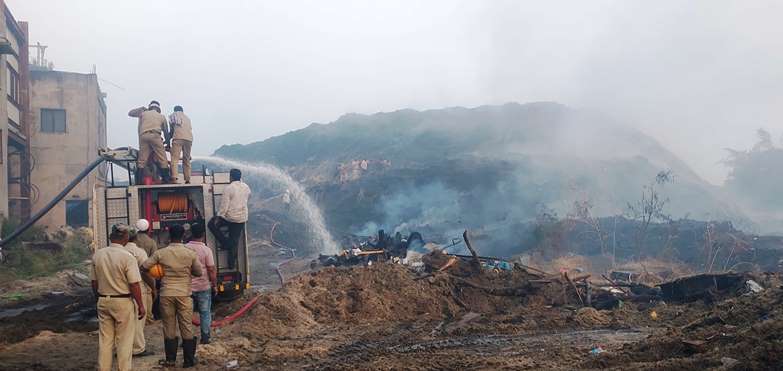 ಕಬ್ಬಿನ ಸಿಪ್ಪೆಯ ದಿಮ್ಮೆಗೆ ಹೊತ್ತಿಕೊಂಡ ಬೆಂಕಿಯನ್ನು ನಂದಿಸುತ್ತಿರುವ ಅಗ್ನಿಶಾಮಕ ದಳ ಸಿಬ್ಬಂದಿ