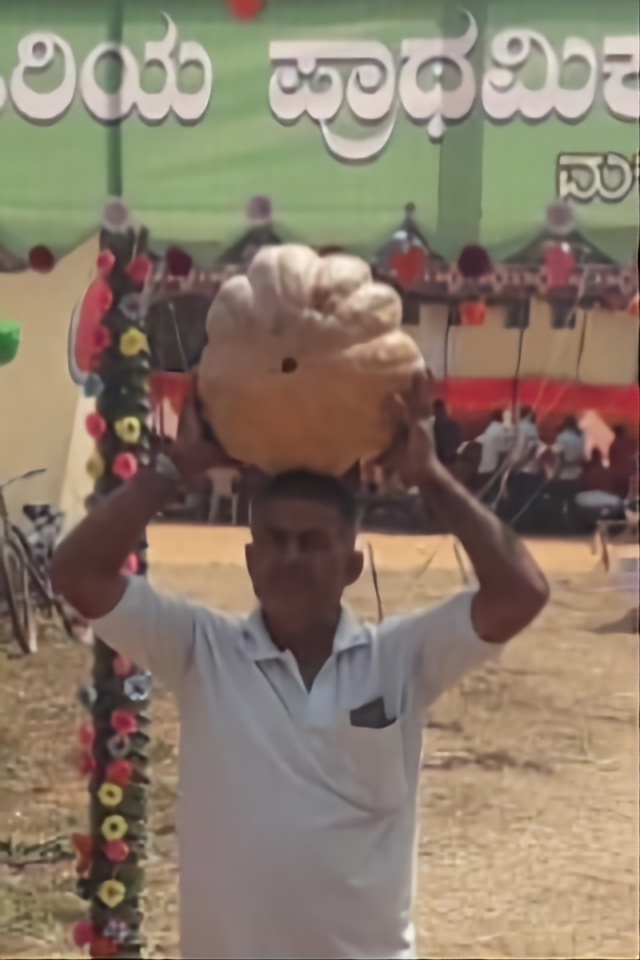 ಗೌಟೂರು ಶಾಲಾ ಮಕ್ಕಳ ಹಳ್ಳಿ ಸಂತೆಯಲ್ಲಿ ಖರೀದಿಸಿದ ದೊಡ್ಡ ಗಾತ್ರದ ಚೀನಿಕಾಯಿಯನ್ನು ತಲೆಯ ಮೇಲೆ ಹೊತ್ತು-ಯುತ್ತಿರುವ ಗ್ರಾಹಕ