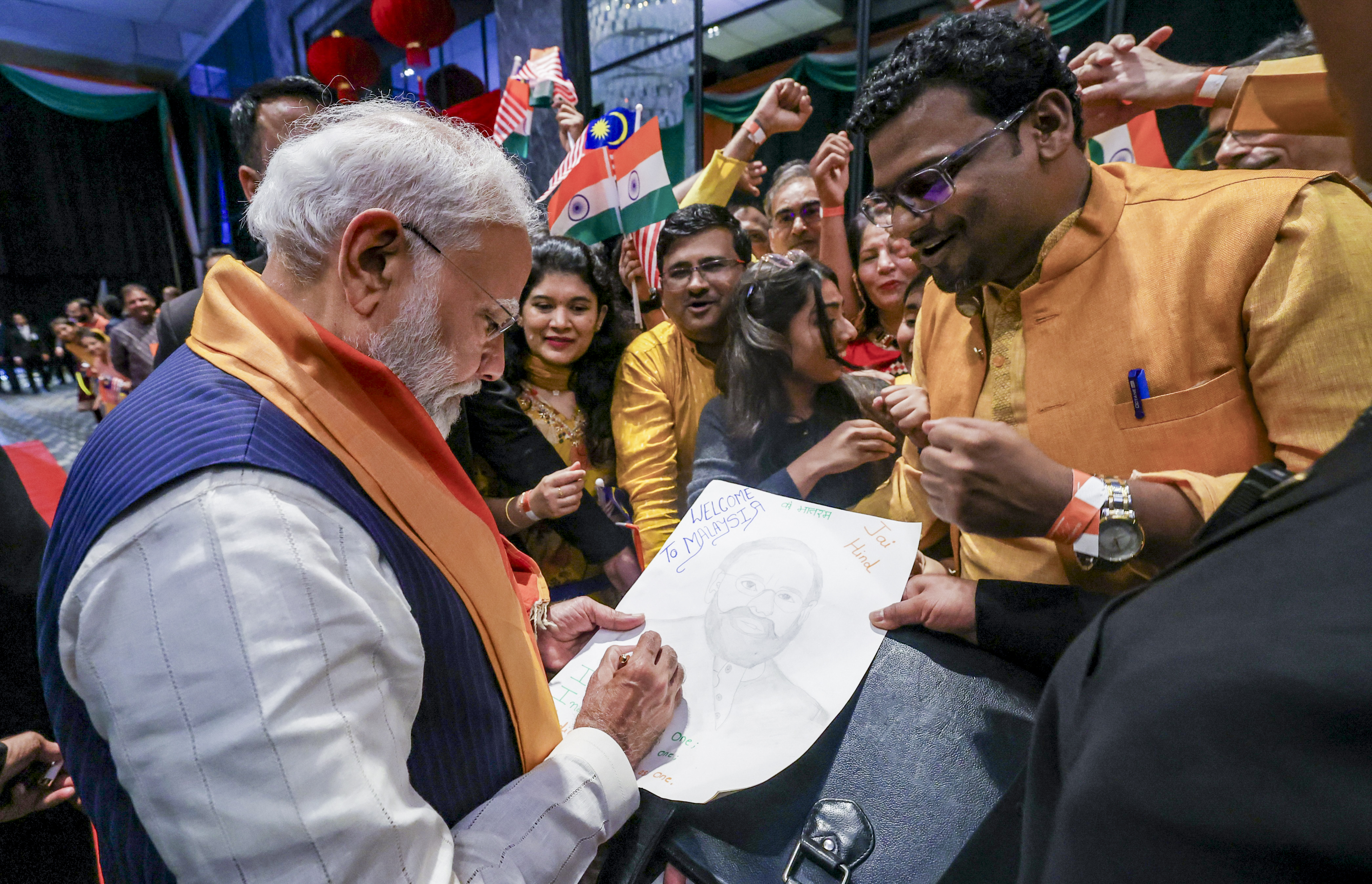 ಕ್ವಾಲಾಲಂಪುರದಲ್ಲಿ ನಡೆದ ಭಾರತೀಯ ಸಮುದಾಯದವರ ಕಾರ್ಯಕ್ರಮದಲ್ಲಿ ವ್ಯಕ್ತಿಯೊಬ್ಬರಿಗೆ ಪ್ರಧಾನಿ ನರೇಂದ್ರ ಮೋದಿ ಅವರು ಹಸ್ತಾಕ್ಷರ ನೀಡಿದರು –ಪಿಟಿಐ ಚಿತ್ರ