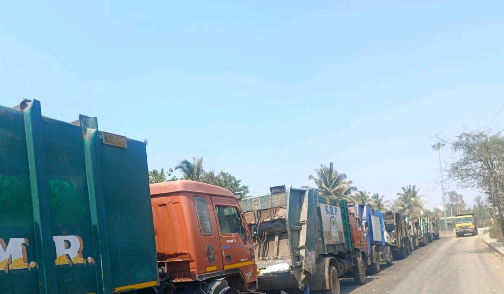 ಬೆಳ್ಳಹಳ್ಳಿ ಮುಖ್ಯರಸ್ತೆಯಲ್ಲಿ ಸಾಲುಗಟ್ಟಿ ನಿಂತಿರುವ ತ್ಯಾಜ್ಯ ತುಂಬಿದ ಲಾರಿಗಳು