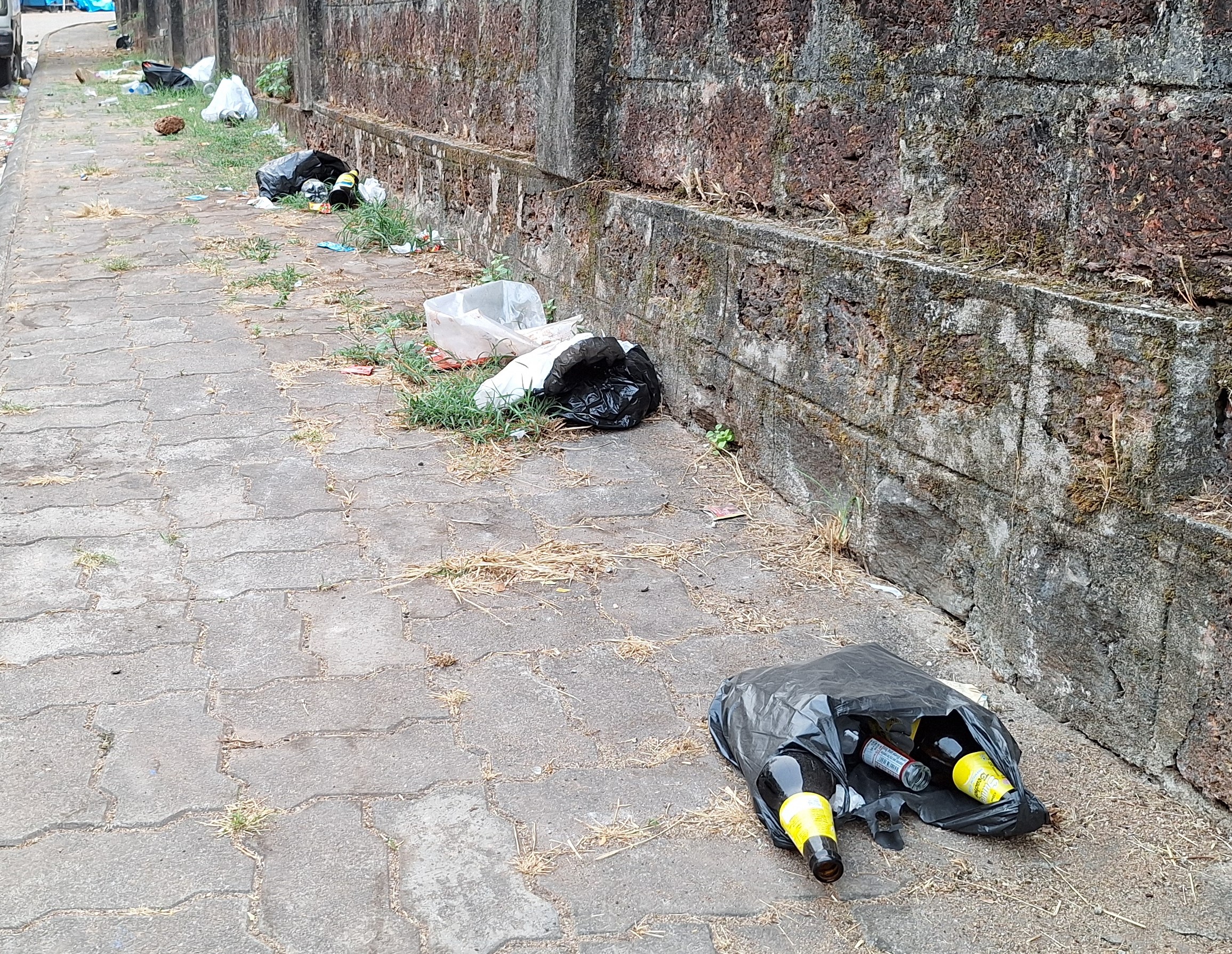 ಪಾದಚಾರಿ ಮಾರ್ಗದ ನಡುವೆ ಎಸೆದಿರುವ ಮದ್ಯದ ಬಾಟಲಿಗಳು