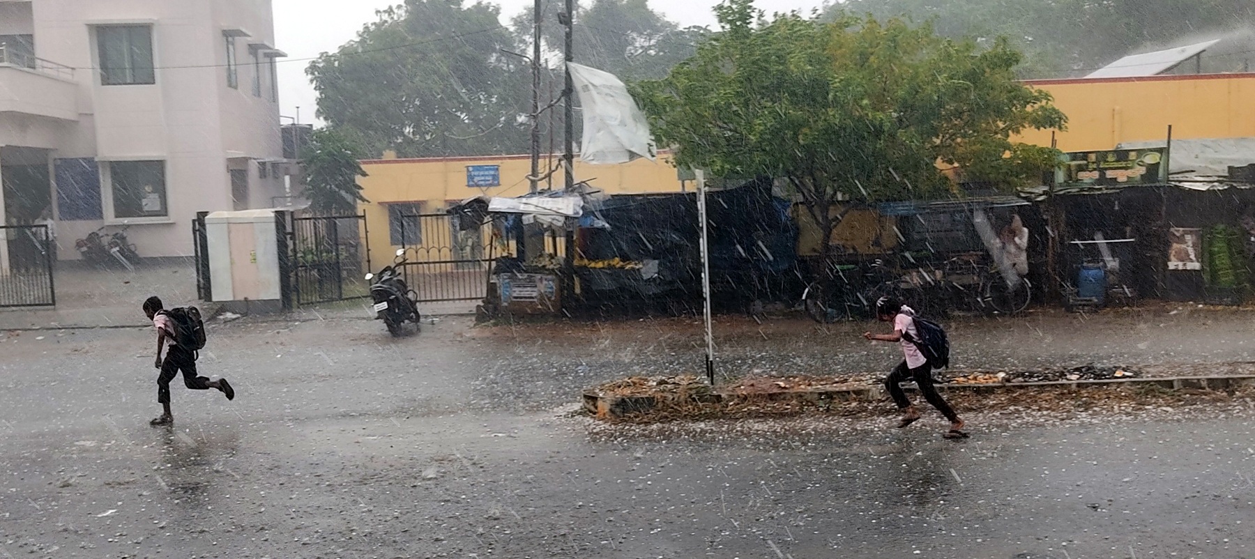 ಸಂತೇಮರಹಳ್ಳಿ ಬಳಿ ಆಲಿಕಲ್ಲು ಮಳೆಯಿಂದ ರಕ್ಷಣೆ ಪಡೆಯಲು ಓಡುತ್ತಿರುವ ಶಾಲಾ ವಿದ್ಯಾರ್ಥಿಗಳು