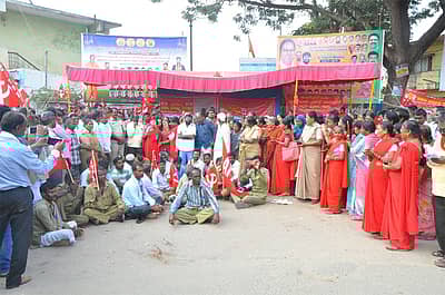 ನಡು ರಸ್ತೆಯಲ್ಲೇ ಕುಳಿತು ಪ್ರತಿಭಟನೆ ನಡೆಸಿದ ಕಾರ್ಮಿಕ ಸಂಘಟನೆಗಳ ಸದಸ್ಯರು