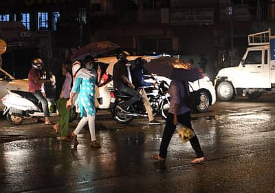 ಮಳೆಯಲ್ಲಿ ರಸ್ತೆ ದಾಟುತ್ತಿರುವ ಜನರು (ಚಿತ್ರ- ಬಿ.ಎಚ್.ಶಿವಕುಮಾರ್)