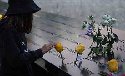 9/11 ದಾಳಿಯ ಸ್ಮರಣಾರ್ಥ ವಿಶ್ವ ವ್ಯಾಪಾರ ಕೇಂದ್ರದ ಸ್ಥಳದಲ್ಲಿ ನಿರ್ಮಿಸಿರುವ ಸ್ಮಾರಕದ ಮುಂದೆ ಕುಳಿತು ಪ್ರೀತಿಪಾತ್ರರನ್ನು ನೆನೆಯುತ್ತಿರುವ ಯುವತಿ