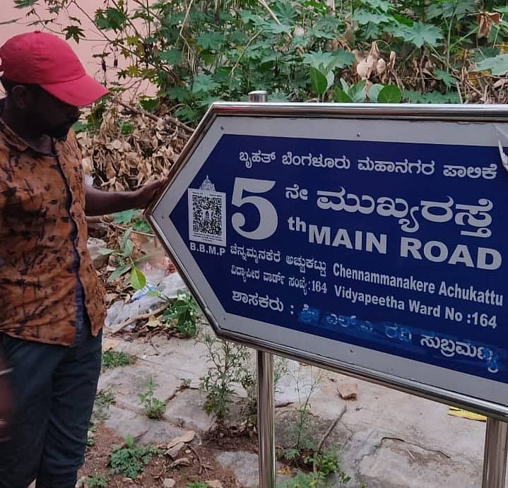 ರಸ್ತೆ ನಾಮಫಲಕದಲ್ಲಿ ಕ್ಯೂಆರ್ ಕೋಡ್ ಅಂಟಿಸುತ್ತಿರುವ ಸಿಬ್ಬಂದಿ