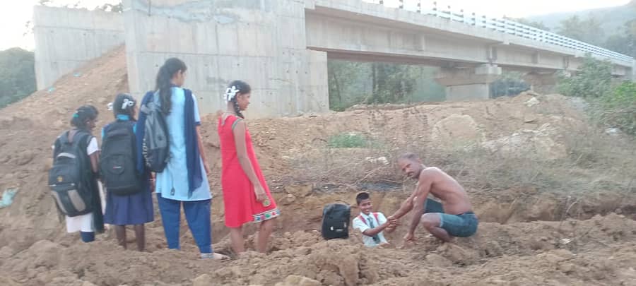 ಕಾರವಾರ ತಾಲ್ಲೂಕಿನ ಉಮಳೆಜೂಗ್ ಗ್ರಾಮದಲ್ಲಿ ಸೇತುವೆ ಬಳಿ ಅಡ್ಡಲಾಗಿ ಕಾಲುವೆ ನಿರ್ಮಿಸಿದ್ದರಿಂದ ದಾಟಲು ಕಷ್ಟಪಡುತ್ತಿದ್ದ ವಿದ್ಯಾರ್ಥಿಯೊಬ್ಬನನ್ನು ಪಾಲಕ ಕೈಹಿಡಿದು ಮೇಲಕ್ಕೆತ್ತುವ ಯತ್ನದಲ್ಲಿ ತೊಡಗಿದ್ದರು 