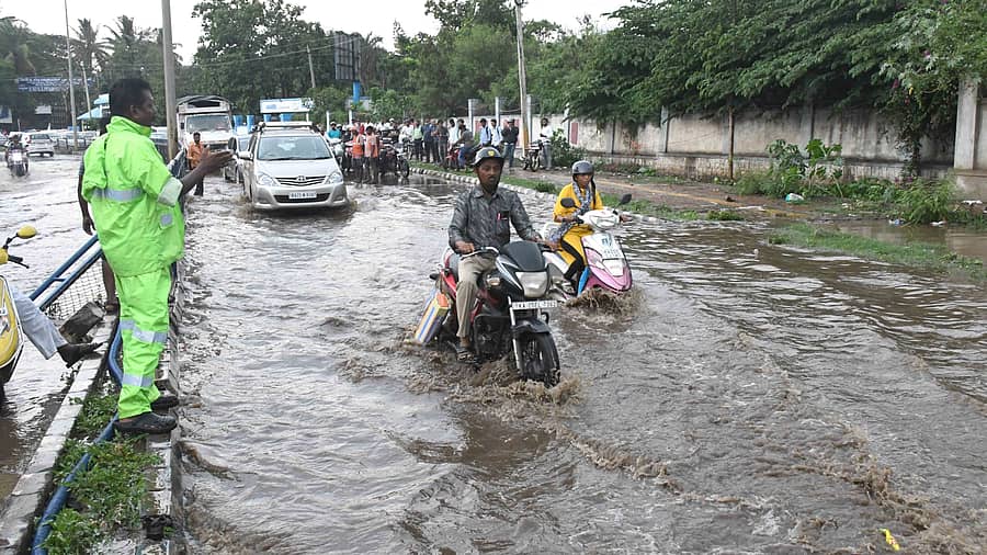 ಧಾರವಾಡದ ಕೆಎಂಎಫ್ ಮುಂಭಾಗದ ರಸ್ತೆಯಲ್ಲಿ ನಿಂತಿದ್ದ ನೀರಿನಲ್ಲಿ ವಾಹನಗಳ ಸಂಚಾರ ಪ್ರಜಾವಾಣಿ ಚಿತ್ರ