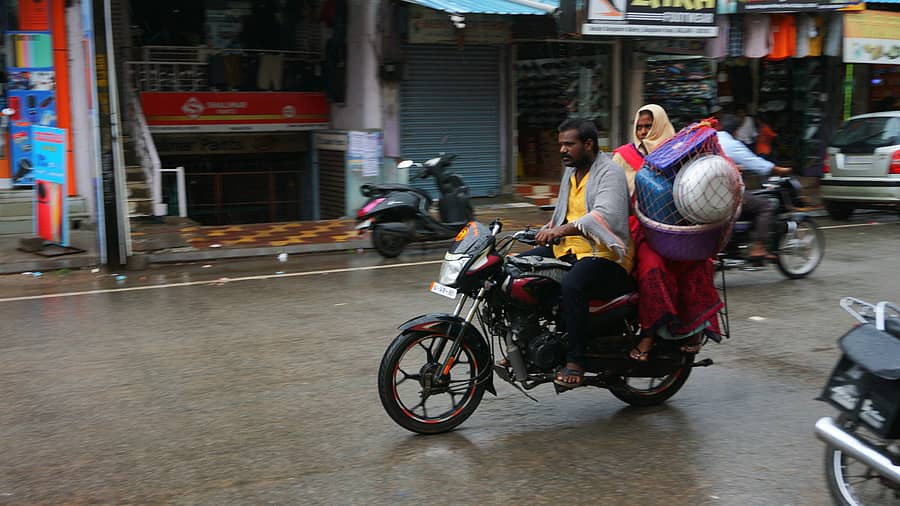 ಜಿಟಿಜಟಿ ಮಳೆಯ ನಡುವೆಯೂ ಮನೆಯ ಪಾತ್ರೆ ಸಾಮಾನುಗಳನ್ನು ಬೈಕ್‌ನಲ್ಲಿಟ್ಟುಕೊಂಡು ಹೊರಟ ದಂಪತಿ ‌ /ಪ್ರಜಾವಾಣಿ ಚಿತ್ರ: ಮುರುಳಿಕಾಂತರಾವ್‌ 
