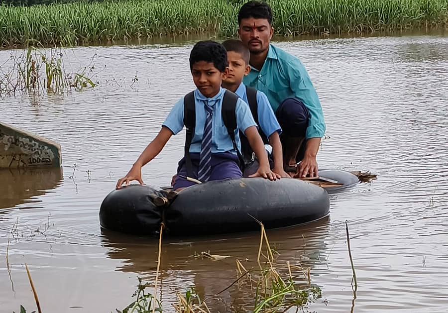 ಹುಲಿಕೆರೆ ಹಿನ್ನೀರಿನಲ್ಲಿ ಶಾಲೆಗೆ ಬಿಡಲು ಮಕ್ಕಳನ್ನು ಟ್ಯೂಬ್ ತೆಪ್ಪದಲ್ಲಿ ಕರೆದುಕೊಂಡು ಬರುತ್ತಿರುವ ಪಾಲಕ