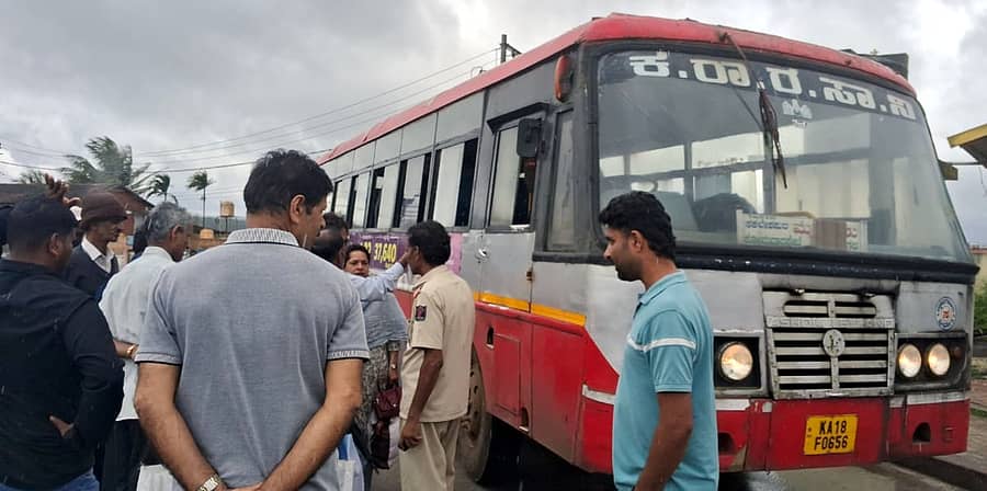 ಸೋಮವಾರಪೇಟೆ ಕೆಎಸ್ಆರ್ಟಿಸಿ ಬಸ್ ನಿಲ್ದಾಣದಲ್ಲಿ ಕಟ್ಟು ನಿಂತಿರುವ ಬಸ್ ಬಗ್ಗೆ ಸಂಚಾರ ನಿಯಂತ್ರಕರನ್ನು ಜನರು ಪ್ರಶ್ನಿಸುತ್ತಿರುವುದು