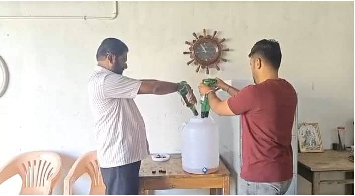 <div class="paragraphs"><p>ನೀರಿನ ಕ್ಯಾನ್‌ಗೆ ಬಾಟಲಿಗಳಿಂದ ಮದ್ಯ ಸುರಿಯುತ್ತಿರುವುದು</p></div>