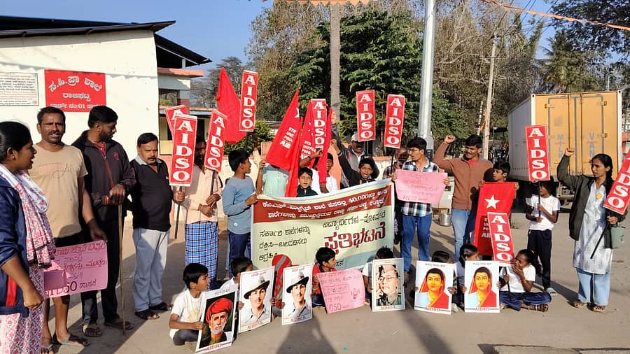 ಹಾಸನದ ರಾಜಘಟ್ಟ ಶಾಲೆಯ ಎದುರು ಶನಿವಾರ ಎಐಡಿಎಸ್ಒ ನೇತೃತ್ವದಲ್ಲಿ ವಿದ್ಯಾರ್ಥಿಗಳು, ಪೋಷಕರು ಪ್ರತಿಭಟನೆ ನಡೆಸಿದರು