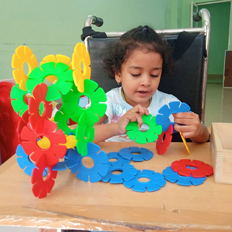 ಮಗುವೊಂದು ಥೆರಪಿ ಸಾಮಾಗ್ರಿ ಹಿಡಿದು ಮಾತಿನ ಚಿಕಿತ್ಸೆ ಪಡೆಯುತ್ತಿರುವುದು