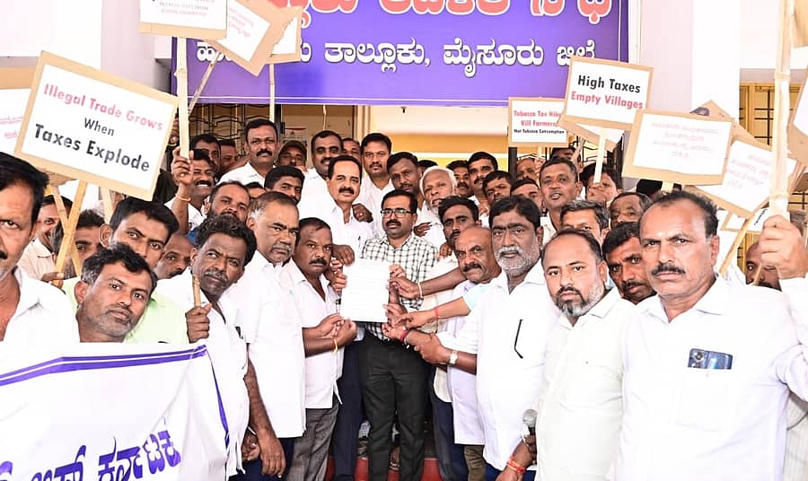ಹುಣಸೂರು ನಗರದಲ್ಲಿ ಕರ್ನಾಟಕ ವರ್ಜೀನಿಯ ತಂಬಾಕು ಬೆಳೆಗಾರರ ಸಂಘದ ಸದಸ್ಯರು ತಂಬಾಕು ಉತ್ಪನ್ನಗಳ ಮೇಲಿನ ತೆರಿಗೆ ಏರಿಕೆ ವಿರುದ್ಧ ಮಂಗಳವಾರ ಬೃಹತ್ ಪ್ರತಿಭಟನೆ ನಡೆಸಿ, ಉಪ ವಿಭಾಗಾಧಿಕಾರಿ ಕಚೇರಿ ತಹಶೀಲ್ದಾರ್ ಯದುಗಿರೀಶ್ ಅವರಿಗೆ ಮನವಿ ಪತ್ರ ನೀಡಿದರು