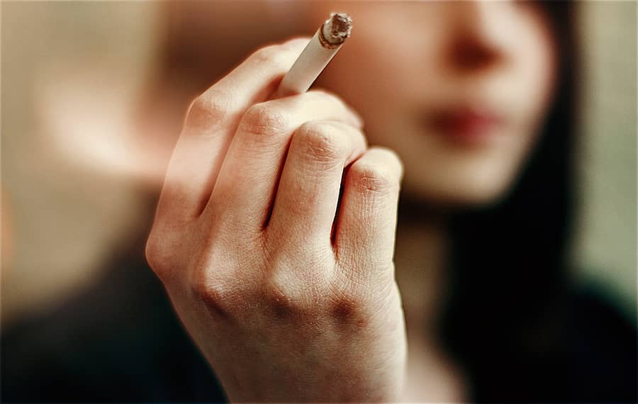 Woman hands holding cigarette outdoor.