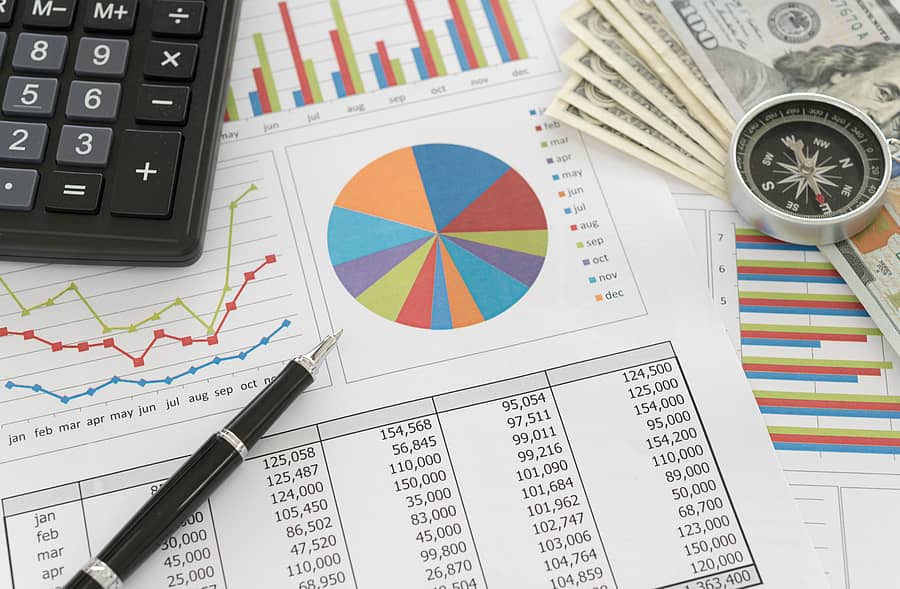 Pen on Pie chart and graphs business report with money, compass, calculator on desk of financial advisor. Accounting and Financial Planning Concept