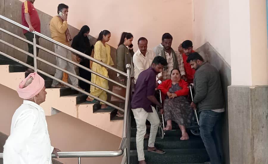 ಶ್ರೀರಂಗಪಟ್ಟಣ ಮಿನಿ ವಿಧಾನಸೌಧದ ಎರಡನೇ ಮಹಡಿಯಲ್ಲಿರುವ ಉಪ ನೋಂದಣಾಧಿಕಾರಿ ಕಚೇರಿಗೆ ಜಮೀನು ವಿಕ್ರಯಕ್ಕೆ ಬಂದಿದ್ದ ವೃದ್ಧೆಯನ್ನು ಗಾಲಿ ಕುರ್ಚಿಯ ಸಹಾಯದಿಂದ ಕೆಳಗೆ ಇಳಿಸುತ್ತಿರುವುದು