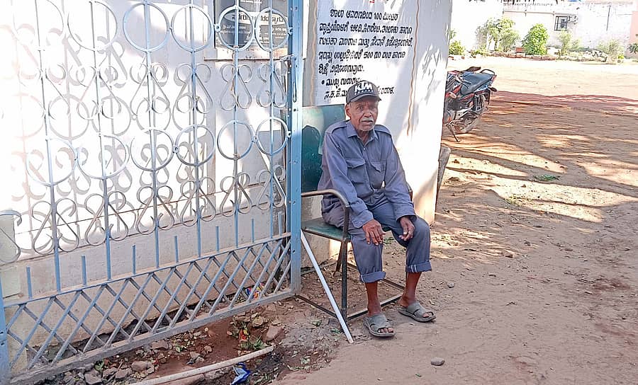 ತೇರದಾಳದ ಸಕರ್ಾರಿ ಶಾಲೆಯ ಗೇಟ್ ಬಳಿ ಕುಳಿತು ಕಾವಲು ಕಾಯುತ್ತಿರುವ ಸೆಕ್ಯುರಿಟಿ.